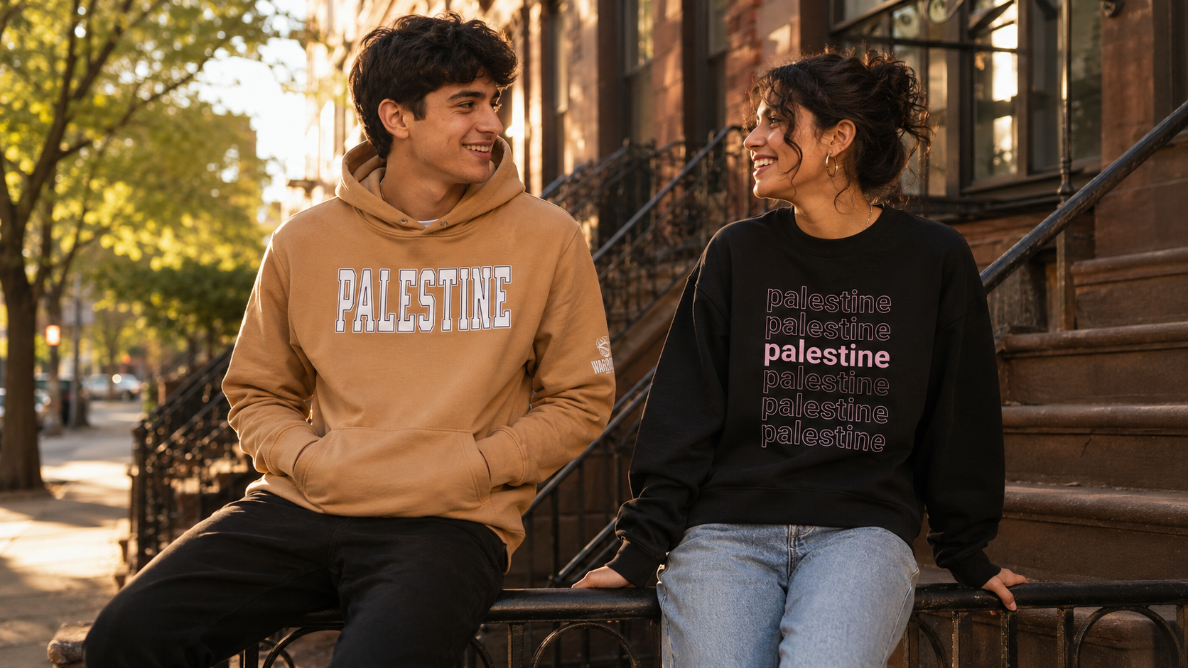 Two people sitting on a stoop with 'Palestine' sweatshirts.
