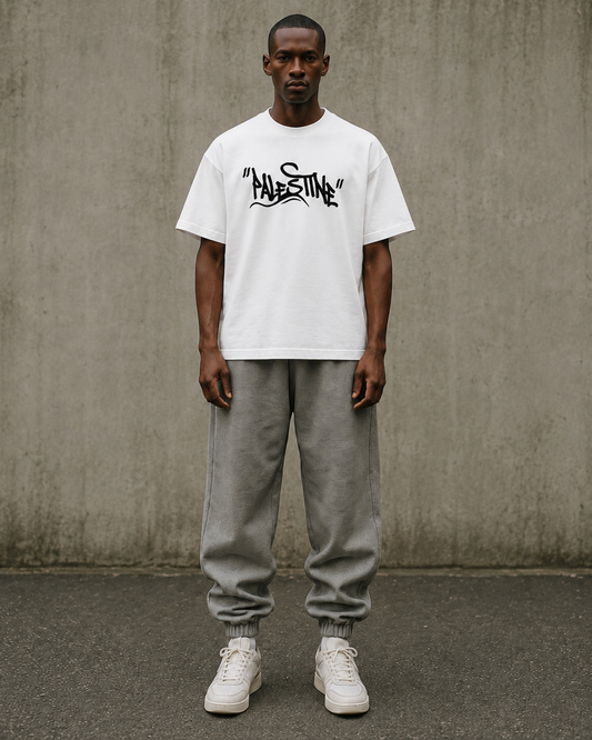 Man wearing a white t-shirt with Palestine written in Graffiti text by Warrior Ink Apparel