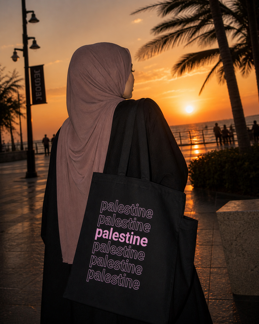 Palestine layered tote bag with stacked typography design in pink worn outdoors at sunset by Warrior Ink Apparel