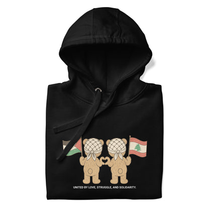 Black hoodie featuring two teddy bears wearing keffiyehs, holding Palestinian and Lebanese flags. Text below reads "United by Love, Struggle, and Solidarity."